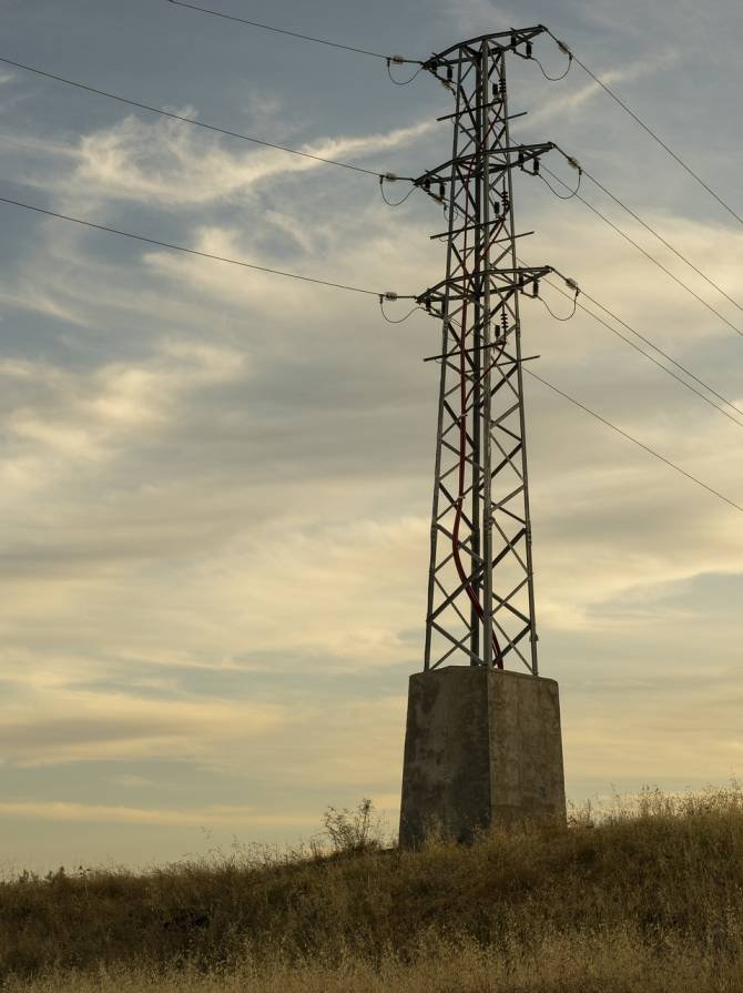 A high voltage electric transmission tower against the sky at sunrise